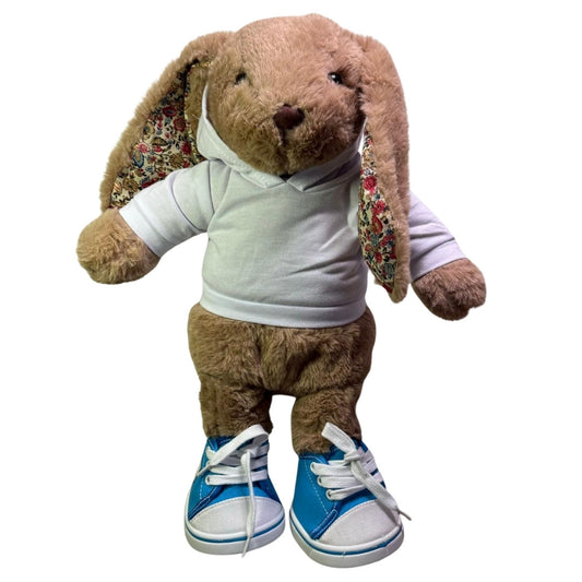 knuffel konijn van Make a Bear heeft hier blauwe sneakers aan. deze schoenen zijn speciaal voor knuffel. Ze zijn blauw en wit van kleur.