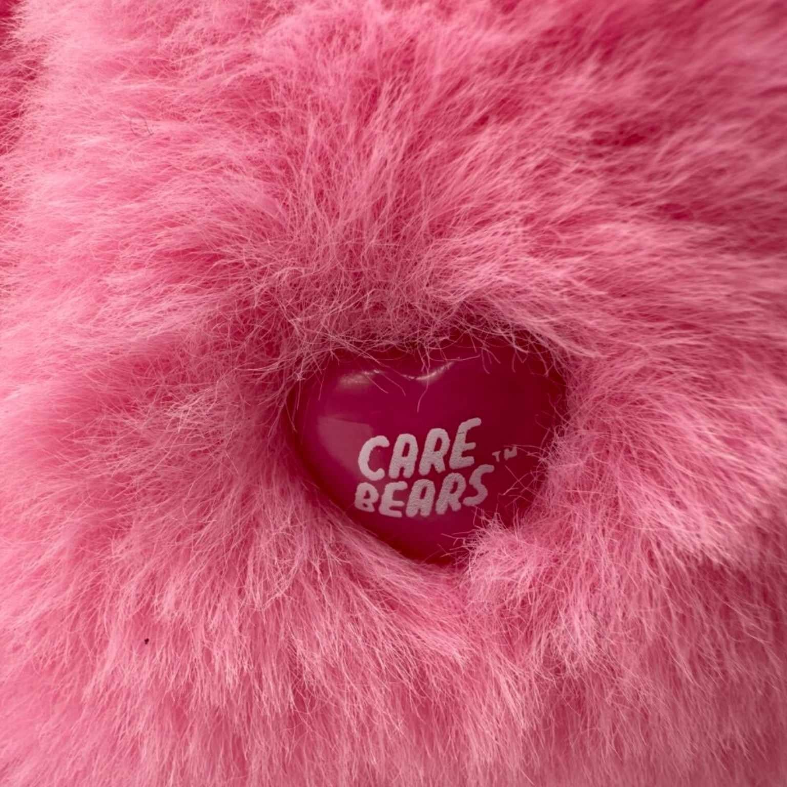 Close-up van het originele Care Bears merkje op het Lachbeertje – officieel gelicentieerde knuffel bij Make a Bear